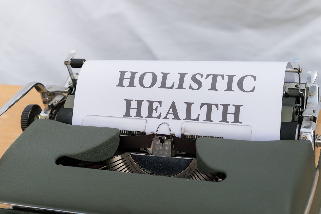 Close-up of a vintage typewriter with Holistic Health typed on paper, symbolizing wellness.
