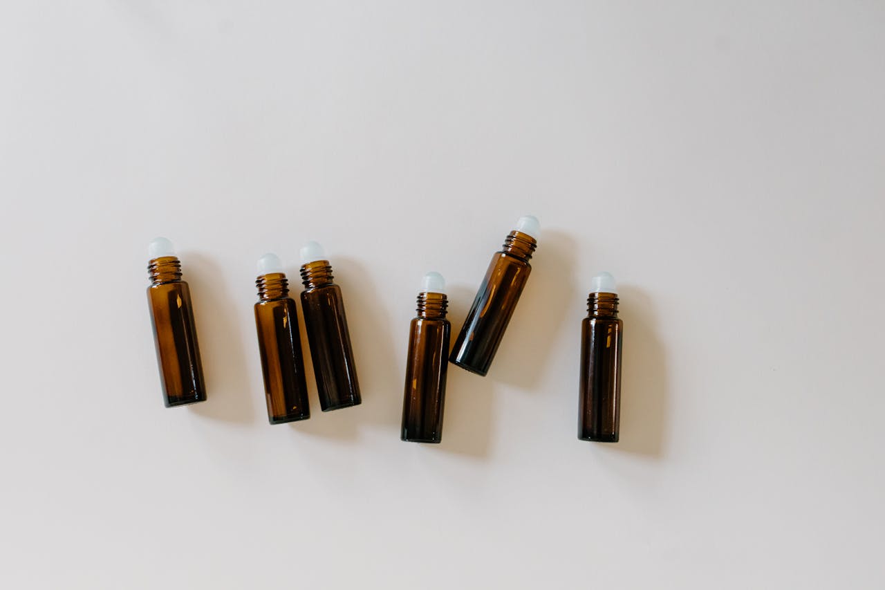 Minimalist arrangement of brown essential oil roller bottles on a clean white surface.