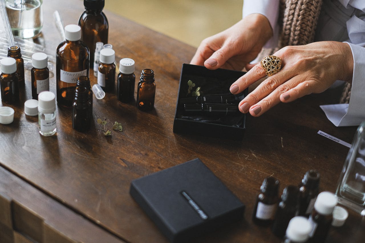 Hands sorting essential oil bottles on a wooden table, highlighting aromatherapy and natural wellness.